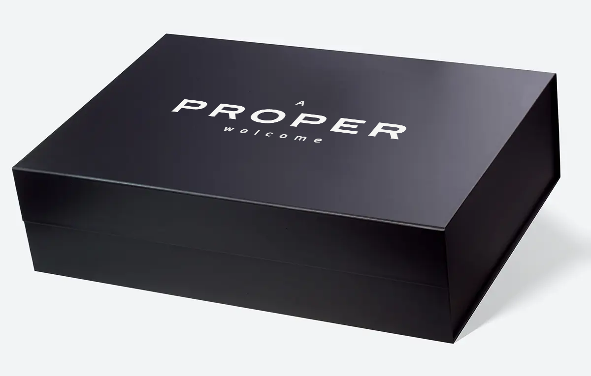 Black Magnetic Gift Box photograph with original A PROPER welcome artwork composited directly onto the lid.